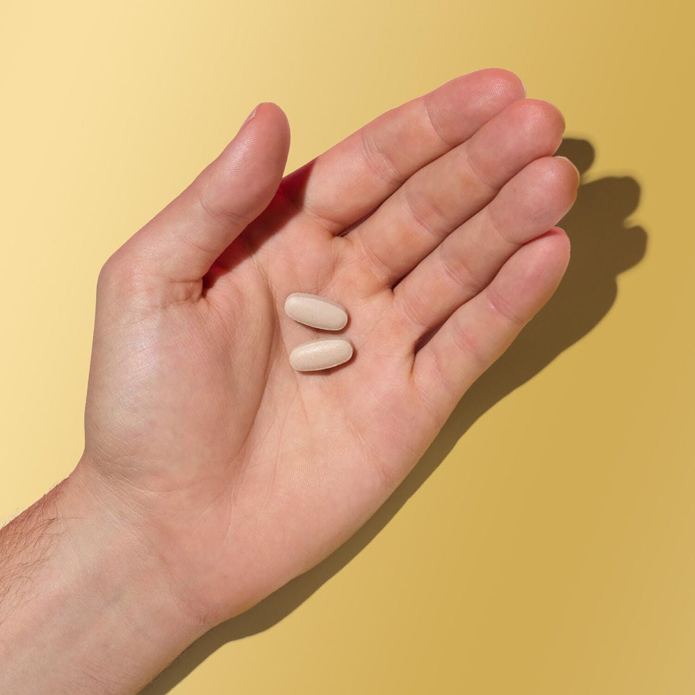 Caplet GNC Mega Men en mano para comparar tamaño y portabilidad