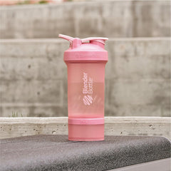 BlenderBottle ProStak en ambiente de gimnasio junto a mochila para llevar suplementos