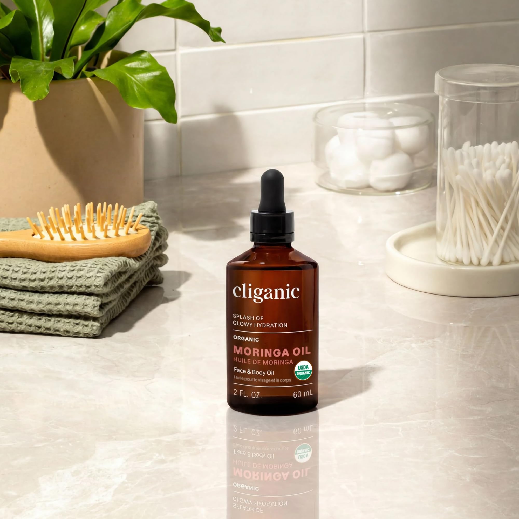 Cliganic aceite de moringa frasco en manos para referencia de tamaño