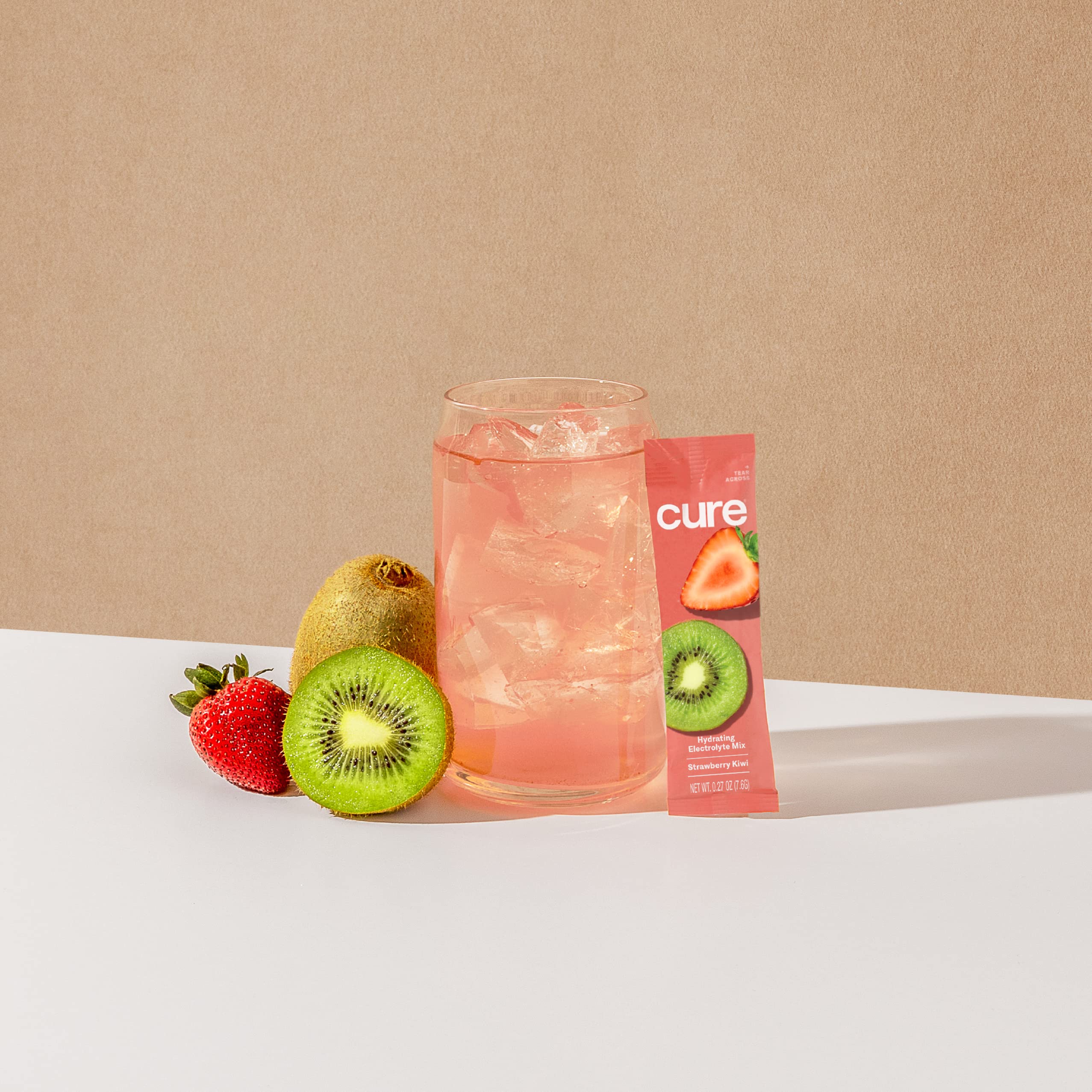Cure Hydration junto a agua de coco y fruta, ingredientes naturales visibles