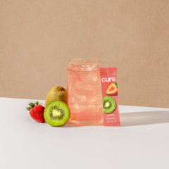 Cure Hydration junto a agua de coco y fruta, ingredientes naturales visibles