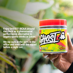 Comparación de tamaño del tarro GHOST BCAA sostenido en mano para referencia de porciones