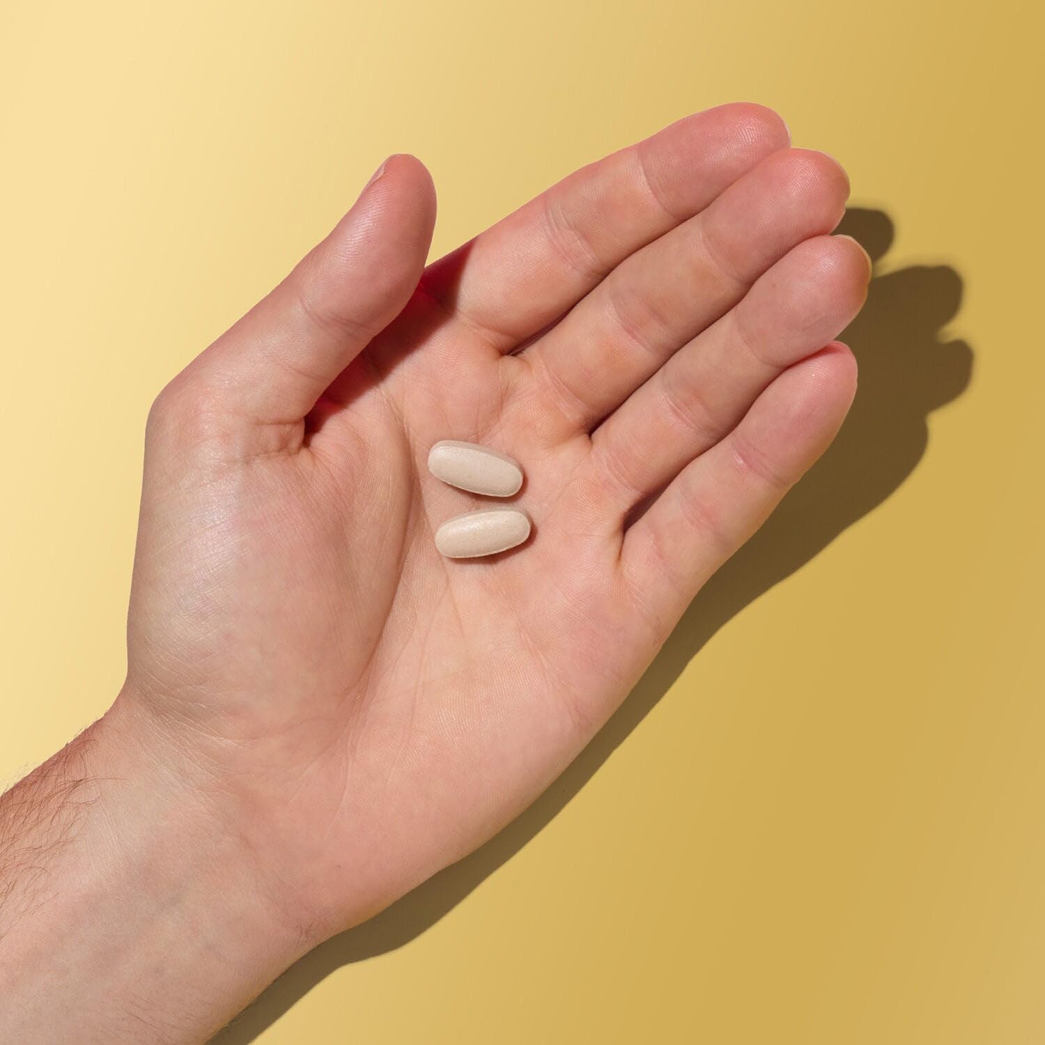 Caplet GNC Mega Men en mano para comparar tamaño y portabilidad