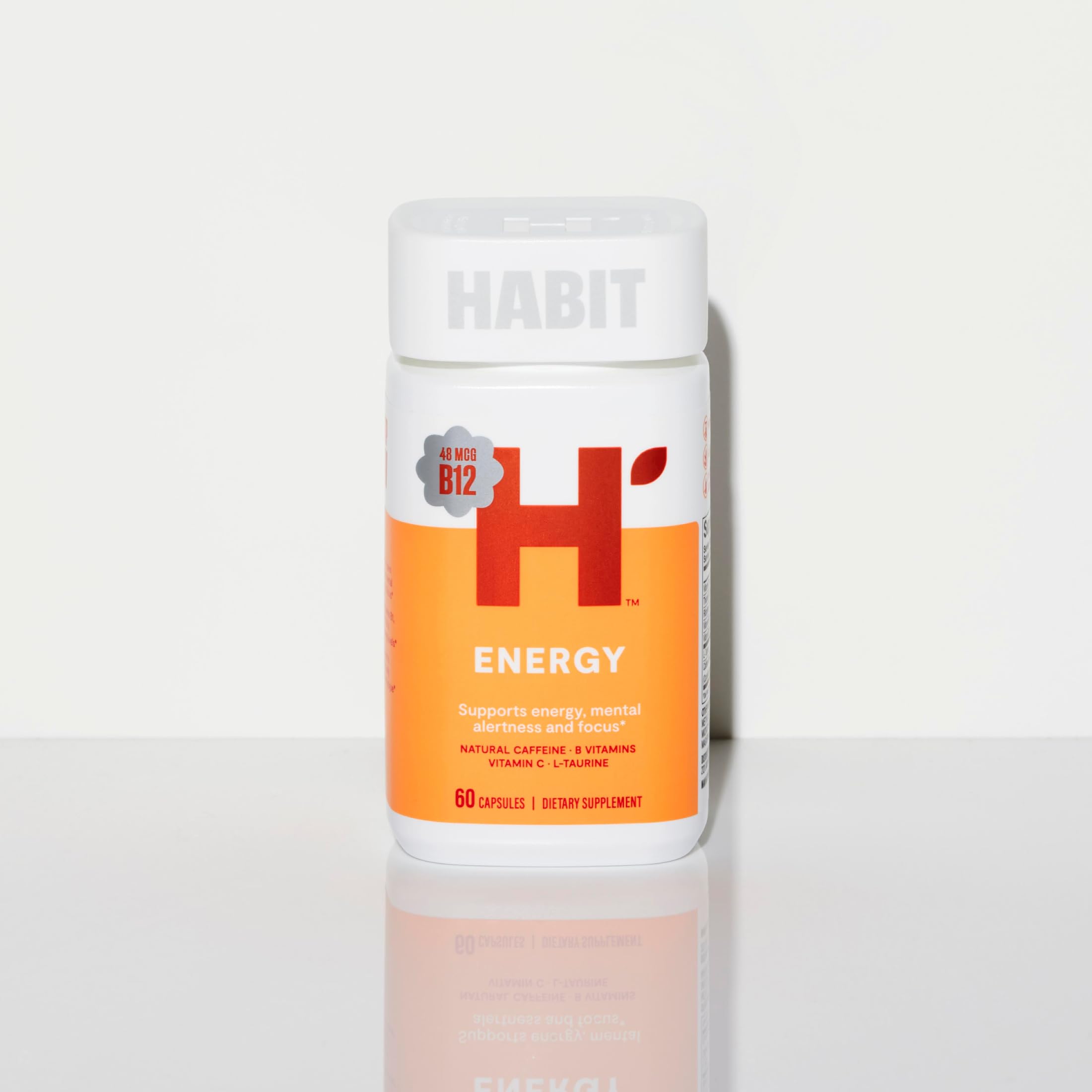 Health By Habit frasco junto a mano para comparar el tamaño de las cápsulas