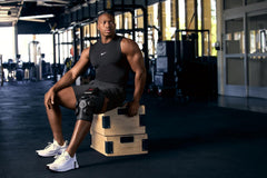 Hyperice X2 Knee junto a mano para comparar tamaño, portátil y práctico
