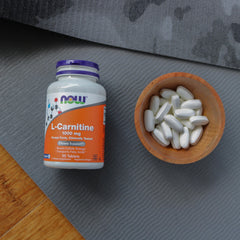 NOW Foods suplemento junto a equipo de gimnasio para apoyo en ejercicio