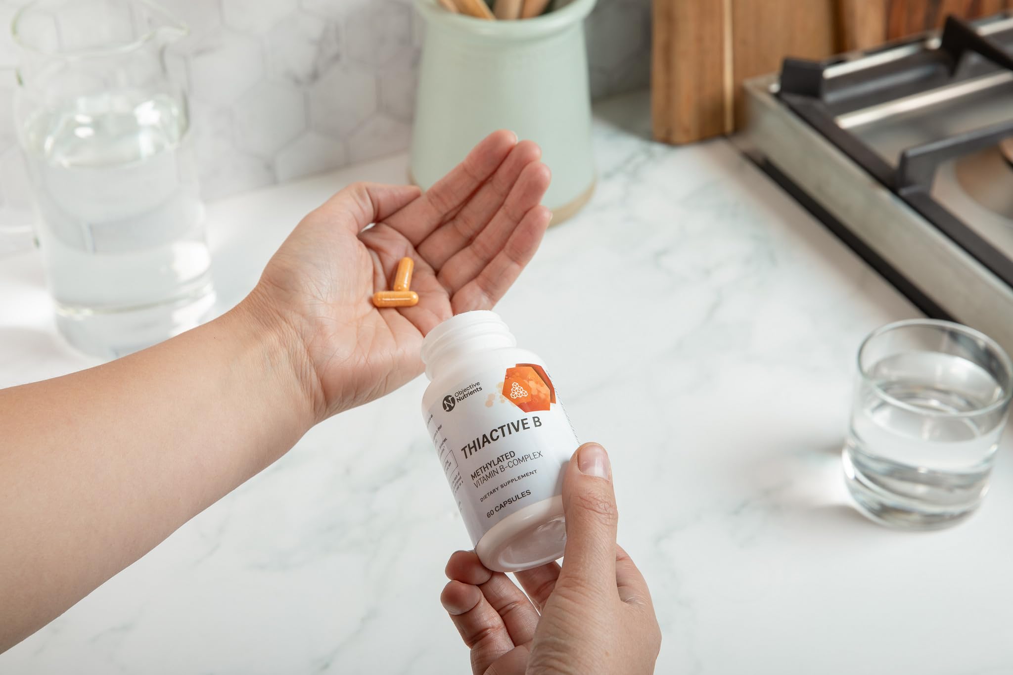 Objective Nutrients cápsula en mano para comparar tamaño y dosificación