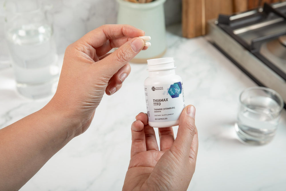 Objective Nutrients Thiamax cápsula en mano para comparar tamaño y dosis conveniente
