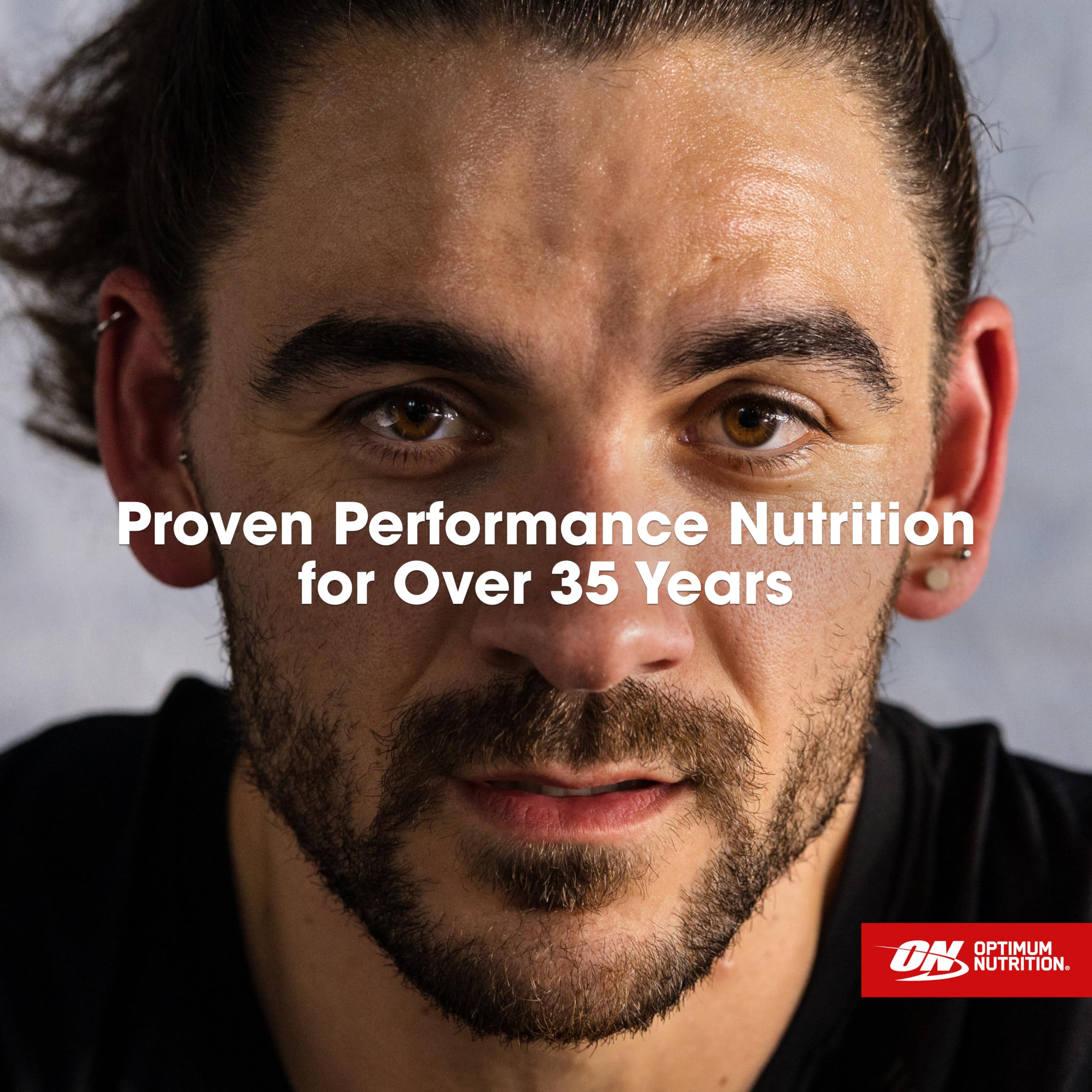 Envase abierto con cuchara medidora Optimum Nutrition, dosificación práctica y precisa