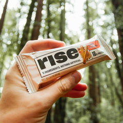 Rise barra sobre mesa junto a botella de agua para un snack post-entreno cómodo