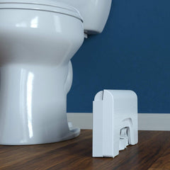 Squatty Potty plegado al lado del inodoro mostrando ahorro de espacio y fácil almacenamiento
