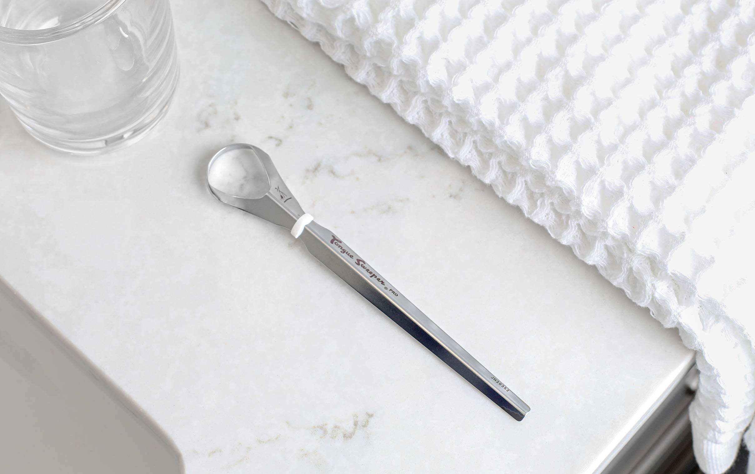 Comparación de tamaño del Tongue Sweeper junto a un cepillo dental para referencia