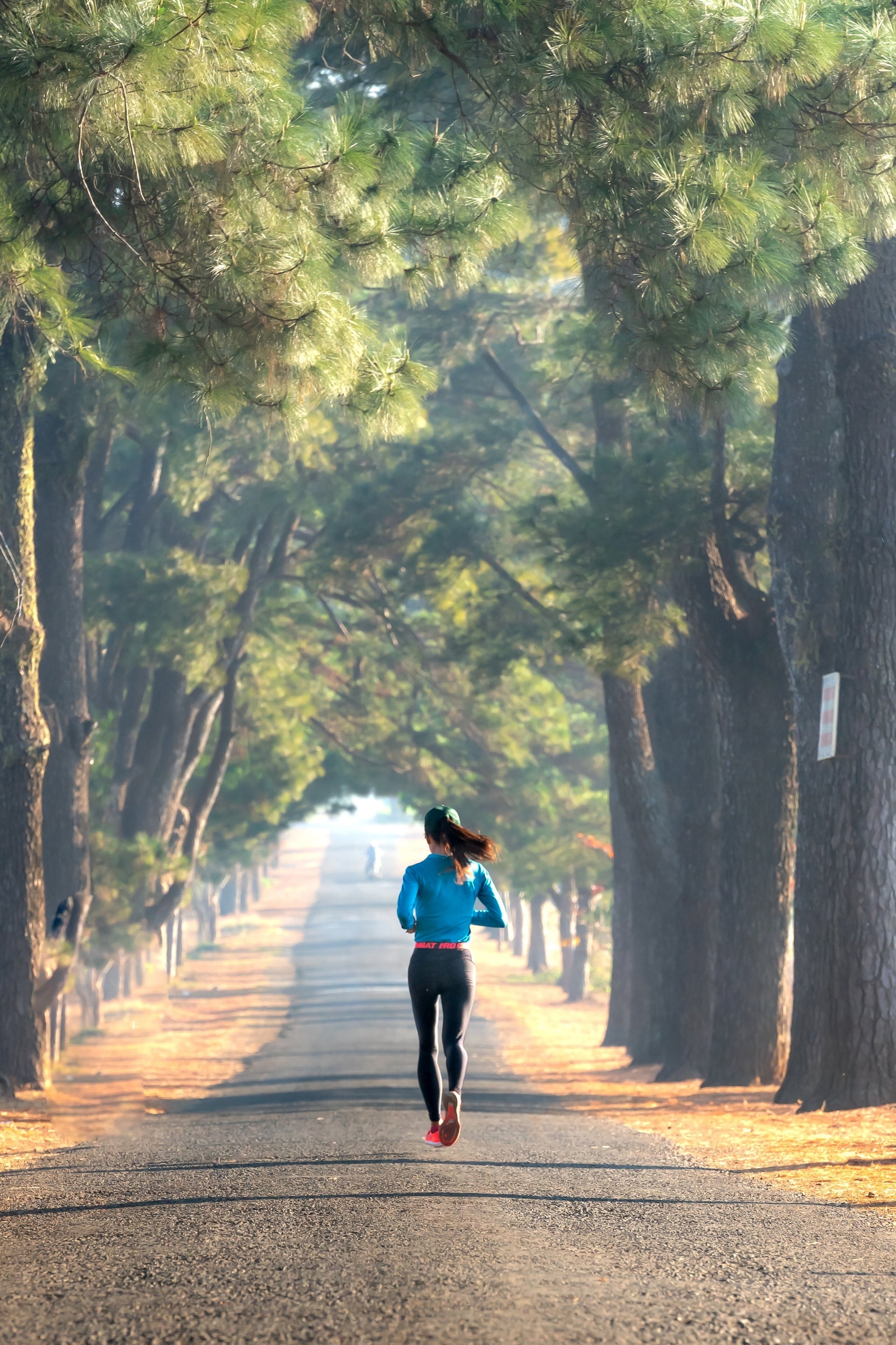 Persona corriendo al aire libre en un camino arbolado, representando el inicio de una historia de bienestar y constancia